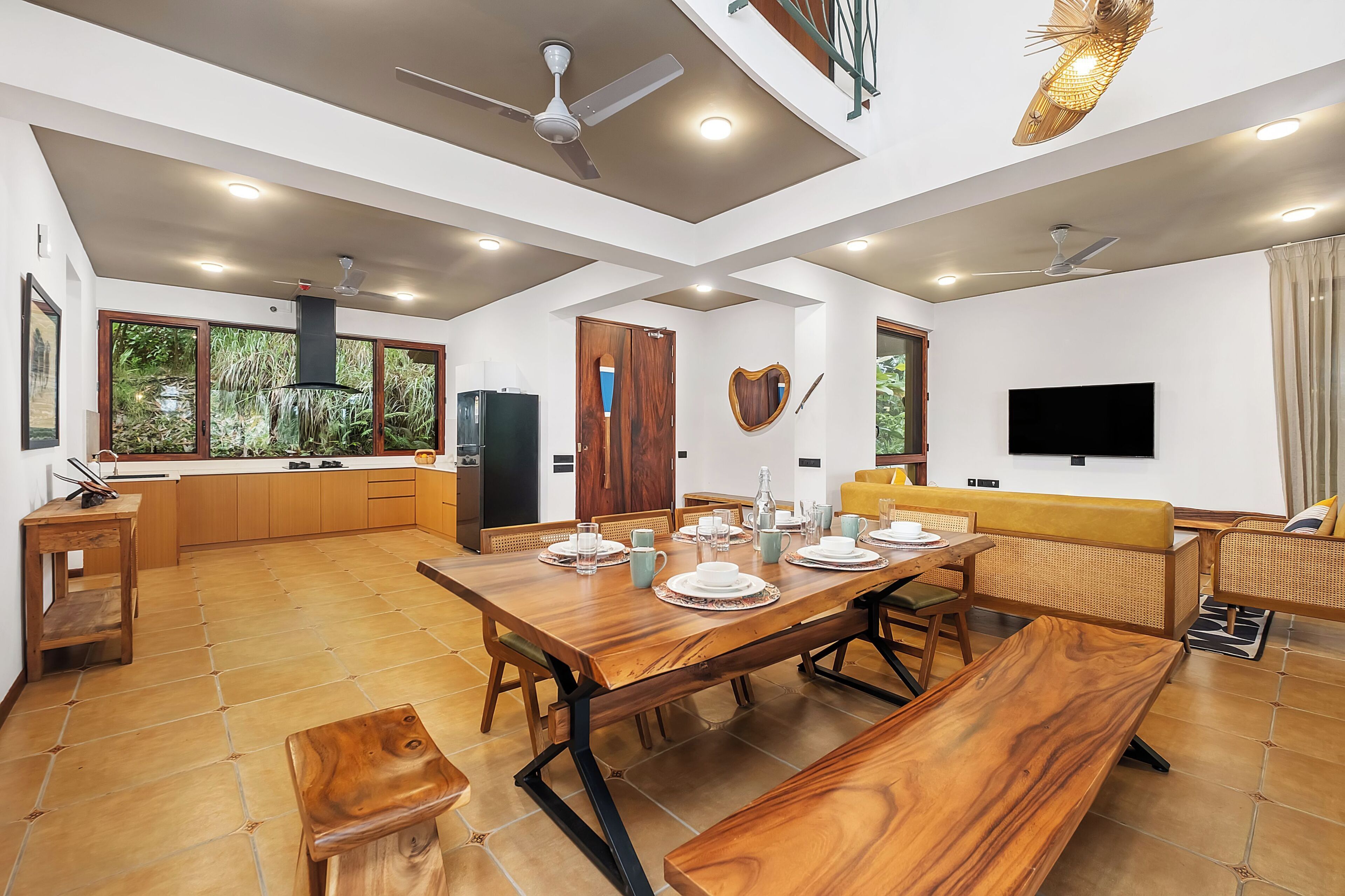 A modern kitchen with a dining area, wooden furniture, and a television.