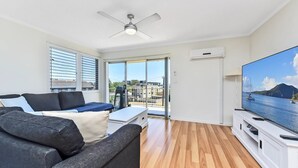 Ein modernes Wohnzimmer mit Sofa, Fernseher und Balkon mit Blick.