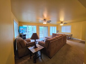 A living room with a sofa, a coffee table, a TV, and a ceiling fan. - Lakefront Cove Retreat, Private Dock, Huge Deck (Rocky Mount)