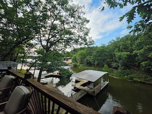 A wooden deck with chairs, a floating dock, and a small house on the water. - Lakefront Cove Retreat, Private Dock, Huge Deck (Rocky Mount)