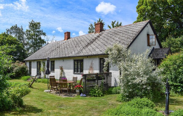 A white house with a sloped roof, a wooden deck, and a garden with a table and chairs. - 3 bedroom cozy home in Smedstorp (Smedstorp)