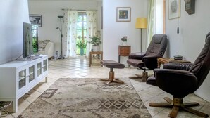 Un salon comprenant un canapé, un fauteuil, une télévision et un meuble.