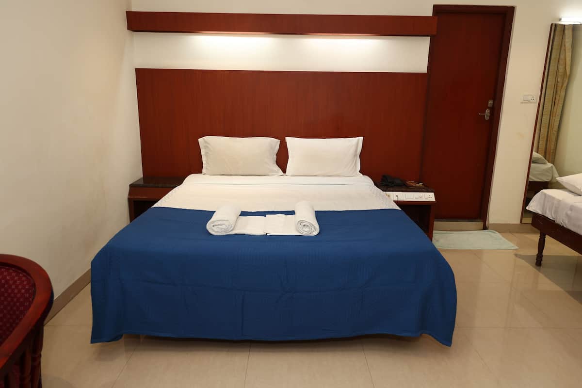 Ein Hotelzimmer mit einem Bett, einem Nachttisch, einem Sessel und einer Tür.