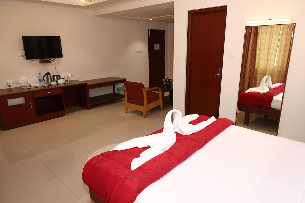 Ein Hotelzimmer mit Bett, Schreibtisch, Stuhl, Fernseher und einer Tür.
