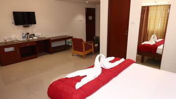 Una habitación de hotel con cama, escritorio, silla, televisor y puerta.