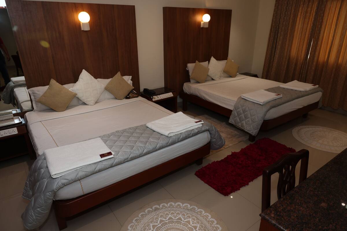 Ein Hotelzimmer mit zwei Betten, Holz-Kopfteilen, Nachttischen und einem roten Teppich.