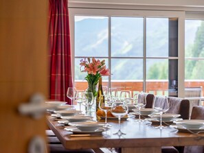 A dining table set with plates, wine glasses, and a vase of flowers. - Top chalet near the slopes and lift in Saalbach (Saalbach-Hinterglemm)