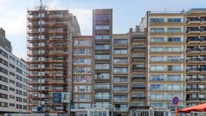 A multi-story building with a modern architectural style, featuring a mix of residential and commercial spaces. - Sea view apartment at the pier. (Blankenberge)