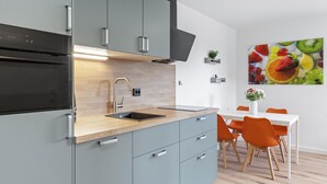 A modern kitchen with grey cabinets, a black oven, and a wooden countertop.