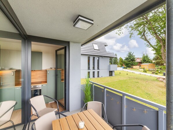 A modern outdoor dining area with a table and chairs, a view of a residential building, and a grassy yard. - 2 Large Apartments by the Baltic Sea (Hohenkirchen OT Beckerwitz)