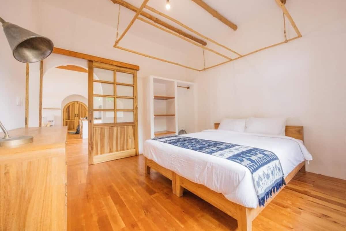 A bedroom with a wooden bed, a desk, and a wardrobe.