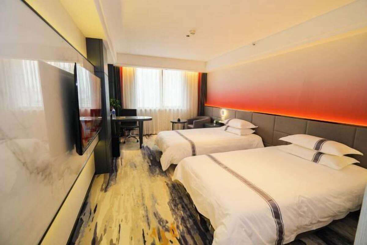 A hotel room with two beds, a desk, a TV, and a red ambient light.
