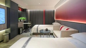 A modern hotel room with a bed, a sofa, a small table, a TV, and a plant. - Gonghui Plaza (Harbin)