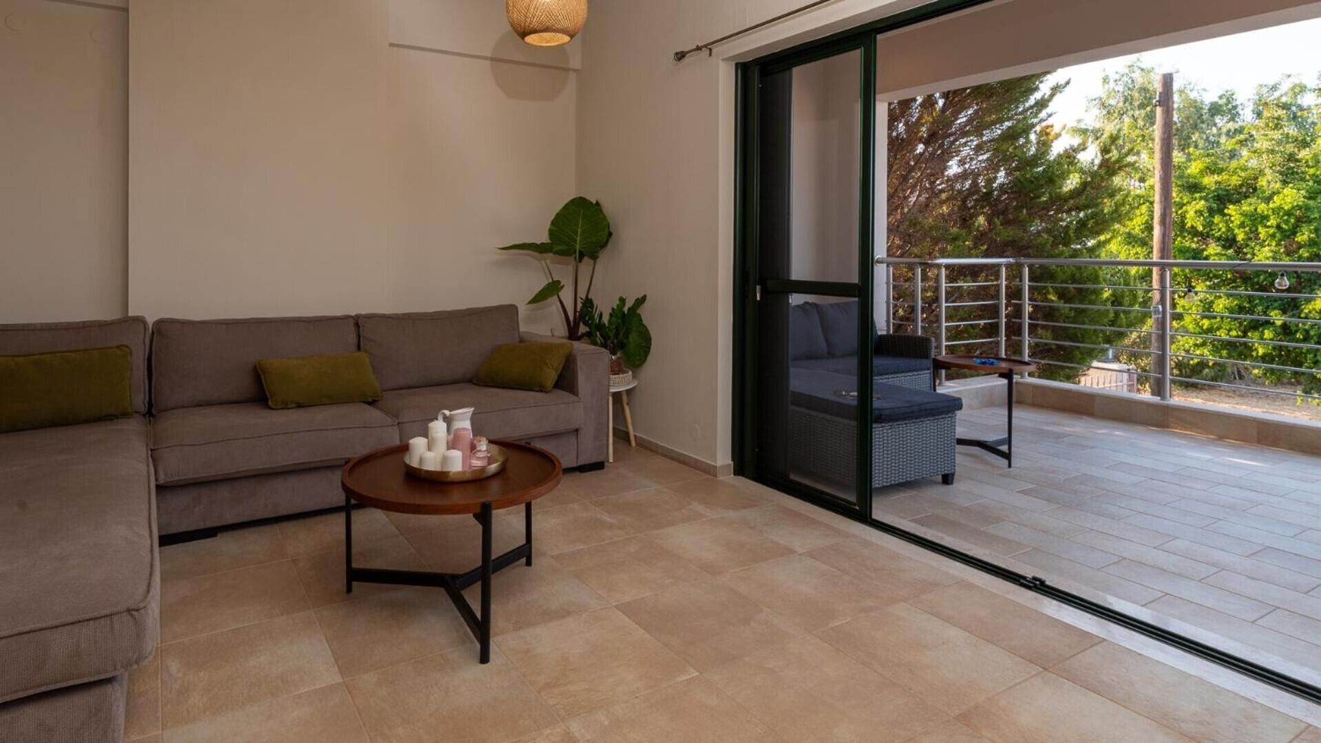 A modern living room with a sofa, a coffee table, and a balcony with outdoor furniture.