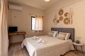 A bedroom with a bed, a desk, a television, and wall art.