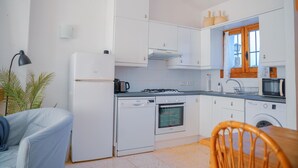 Ett kompakt kök med kylskåp, spis, ugn, mikrovågsugn och tvättmaskin.