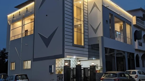 Un edificio moderno de dos pisos con un diseño geométrico llamativo, amplios ventanales y una entrada protegida por una reja.
