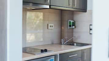 A modern kitchen with stainless steel appliances, a sink, and light-colored tiles.