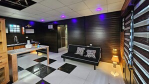 A modern kitchen with a black and white checkered floor, a sofa with patterned cushions, and a small table with a bottle and glasses. - The Studio of Praise - by ZenBreak (Gasparillo)