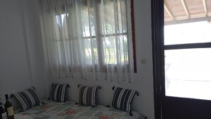 Ein Schlafzimmer mit Bett, Vorhängen, einem Fenster und einer Tür.