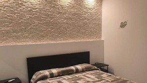 Una camera da letto con un letto, due comodini, una parete con motivo decorativo e un piccolo oggetto decorativo appeso al muro.