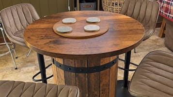 Ein runder Holztisch mit einer zentralen Holzplatte und drei runden Objekten, umgeben von vier gepolsterten Stühlen.