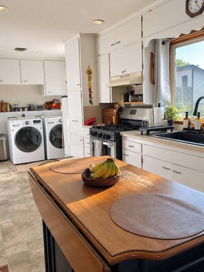 A compact kitchen with white cabinets, a stove, a sink, and a washing machine. - 3BR Chadron home near CSC + fire pit (Chadron)