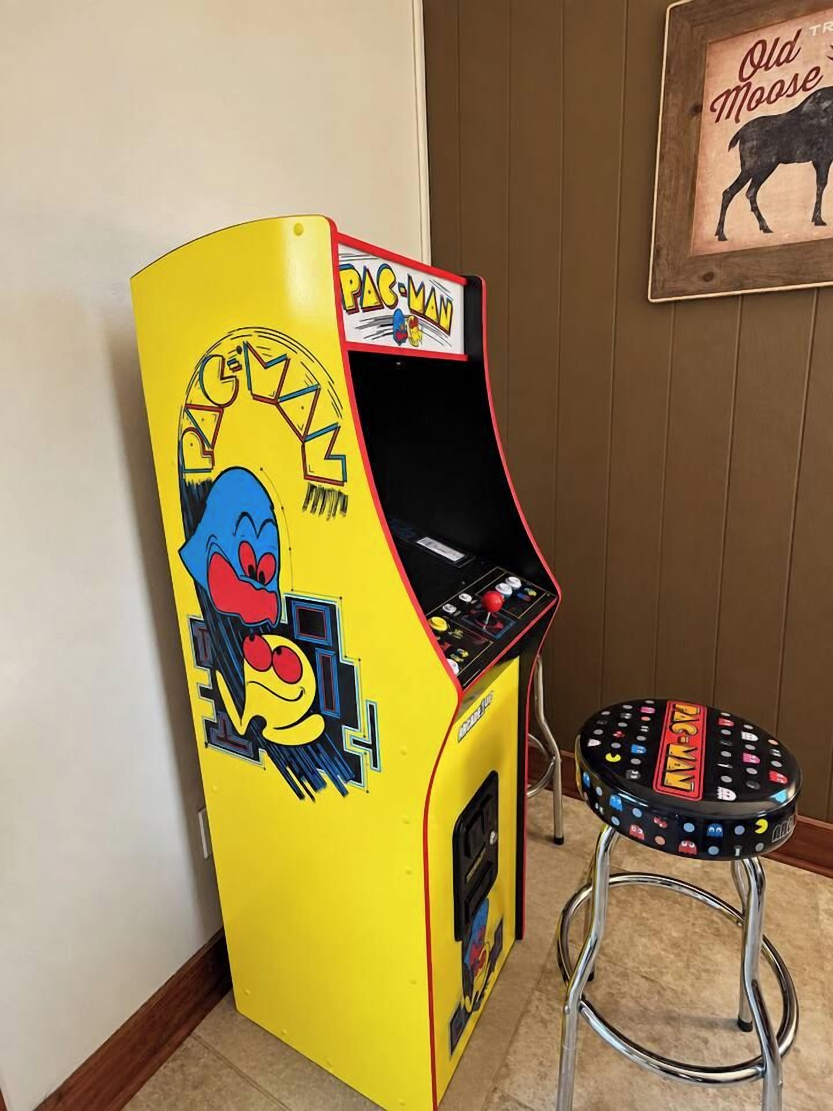 En Pac-Man arkadespilautomat ved siden af en skammel med Pac-Man-motiv.