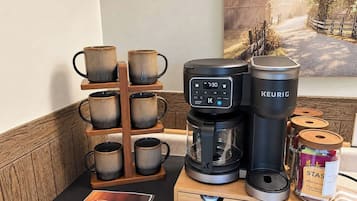 Un espace dédié au café, comprenant une machine à café Keurig, un porte-tasse et un bocal de café décaféiné de la marque STAS.
