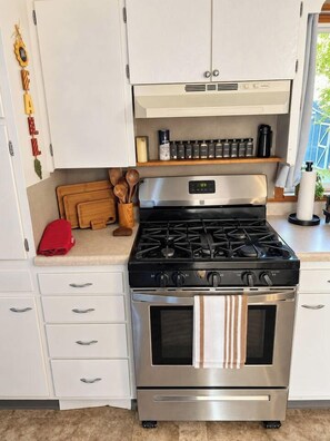 A kitchen with a stainless steel stove, white cabinets, and a wooden countertop. - 3BR Chadron home near CSC + fire pit (Chadron)