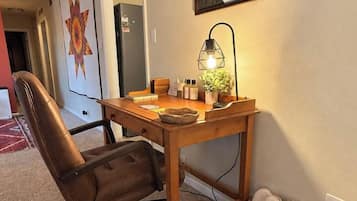 Un bureau à domicile équipé d’un bureau, d’une chaise, d’une lampe et d’œuvres d’art.