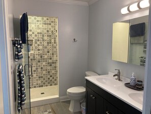 Un bagno con doccia, toilette, lavabo e specchio.