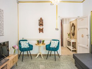 A room with two teal chairs, a small round table with plants, a television, a wardrobe, and a mirror. - Nido nel centro by Interhome (Camaiore)