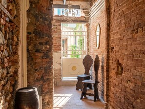 A narrow passageway with stone walls, a wooden barrel, and a rustic wooden chair. - Nido nel centro by Interhome (Camaiore)
