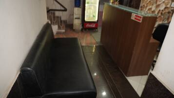 A reception area with a counter, a refrigerator, and a seating area.