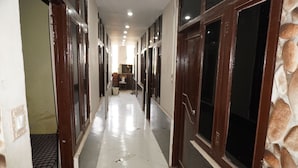 Un pasillo con puertas, piso de baldosas y pared de piedra.