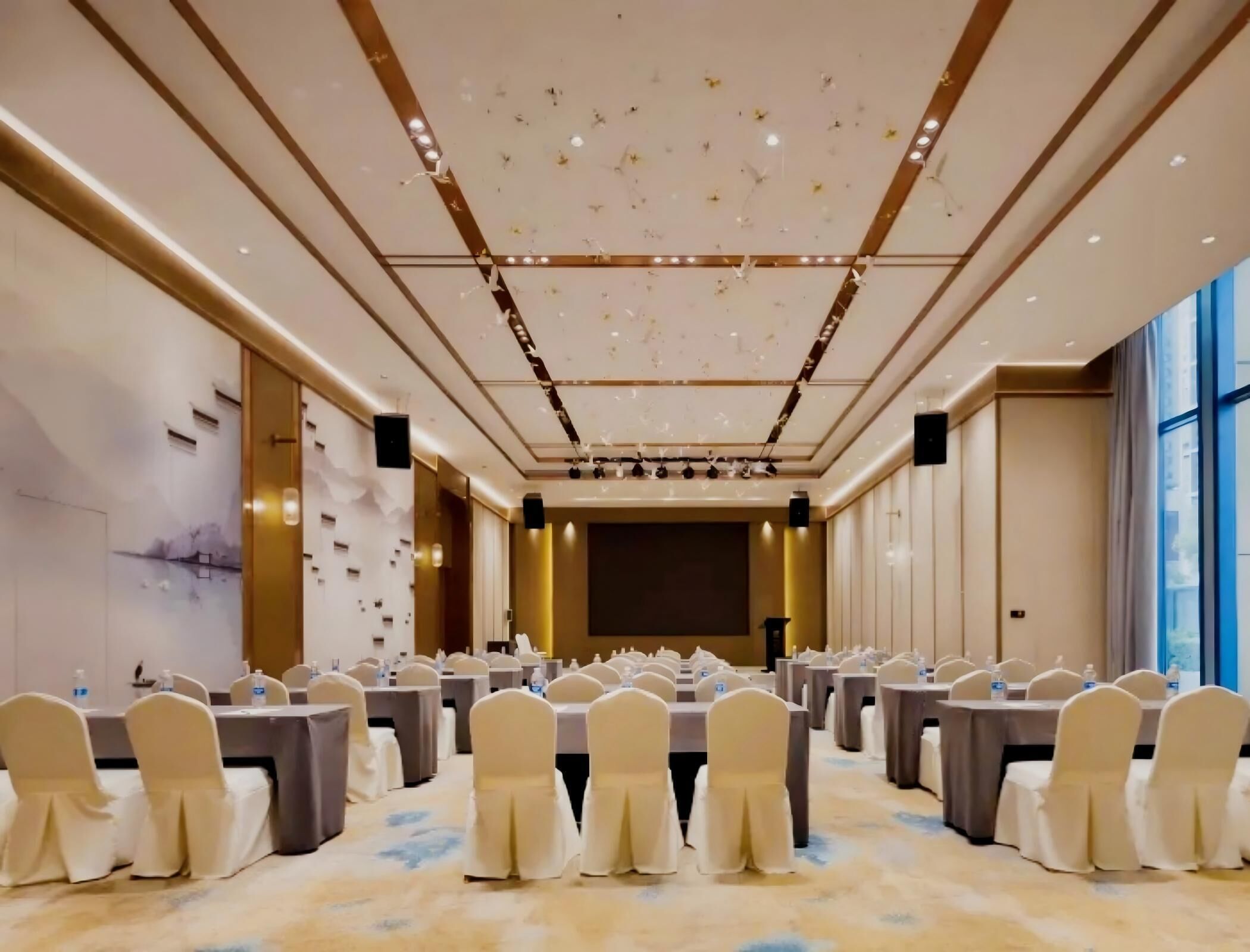 A conference room with tables, chairs, and a stage.