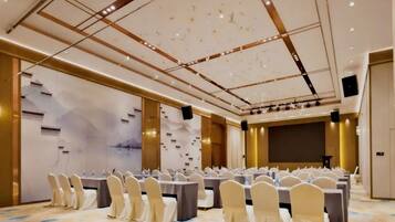 A conference room with rows of tables and chairs, a patterned carpet, and a ceiling with recessed lighting.