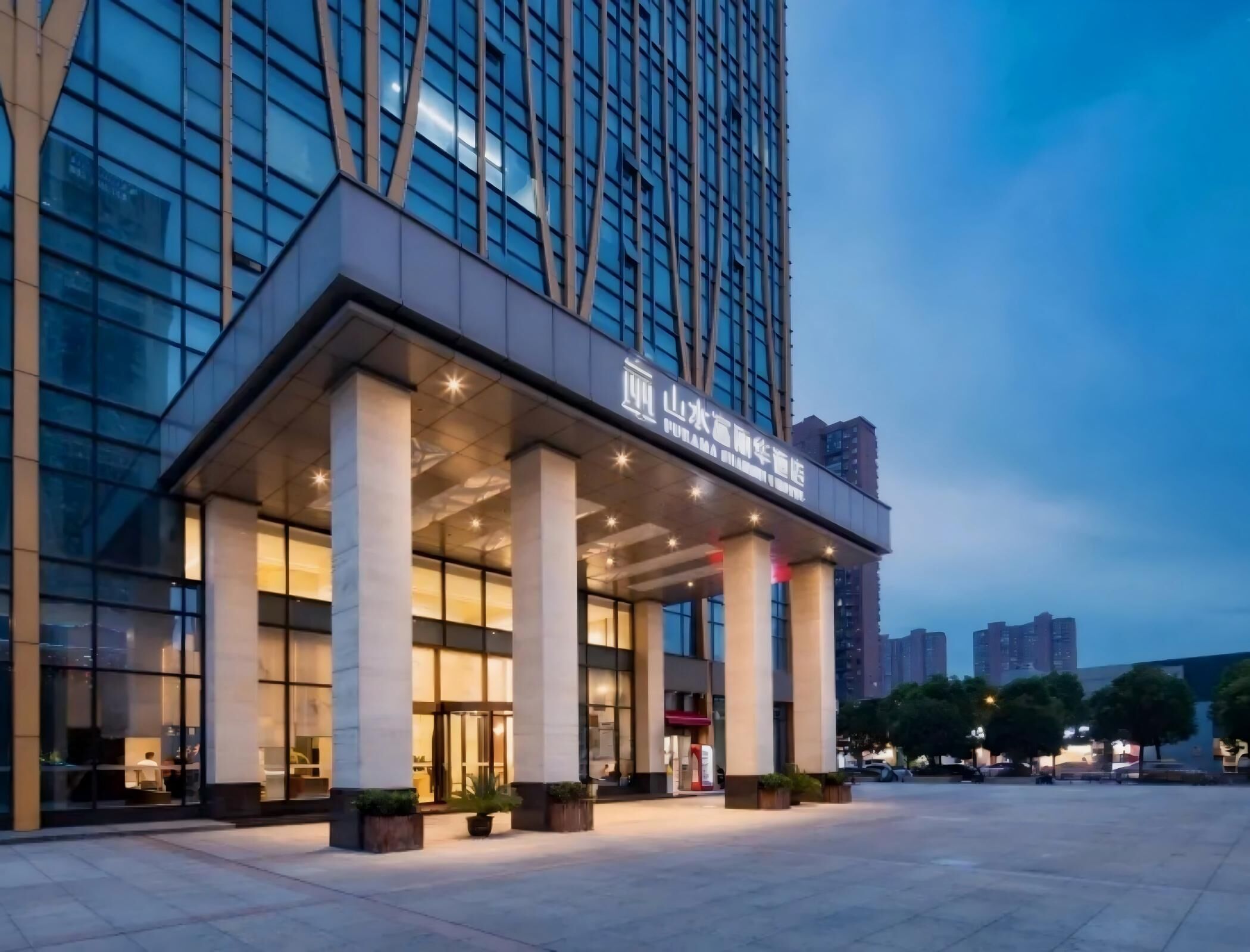 A modern hotel with a prominent entrance, large glass windows, and a well-lit facade.