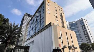 Ett hotell med flera våningar, en framträdande entré i hörnet, stora fönster och en modern arkitektonisk design.