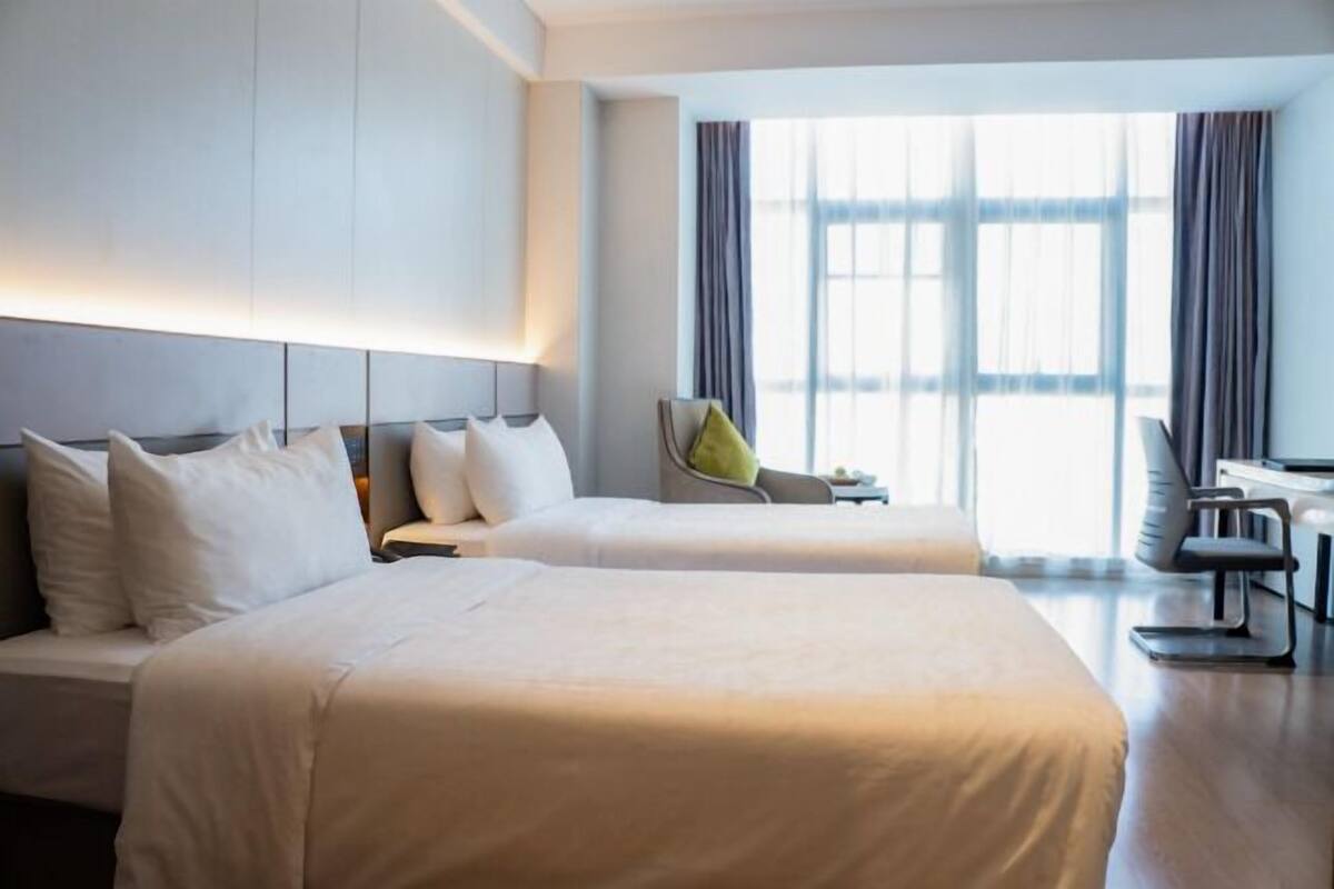 Hotellihuone, jossa on kaksi sänkyä, työpöytä ja tuoli.