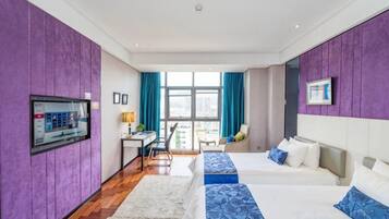 Habitació d'hotel amb dos llits, una taula, una cadira i un finestral gran.