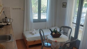 Eine kleine Küche mit Herd, Spüle und einem Essbereich mit Tisch und Stühlen.