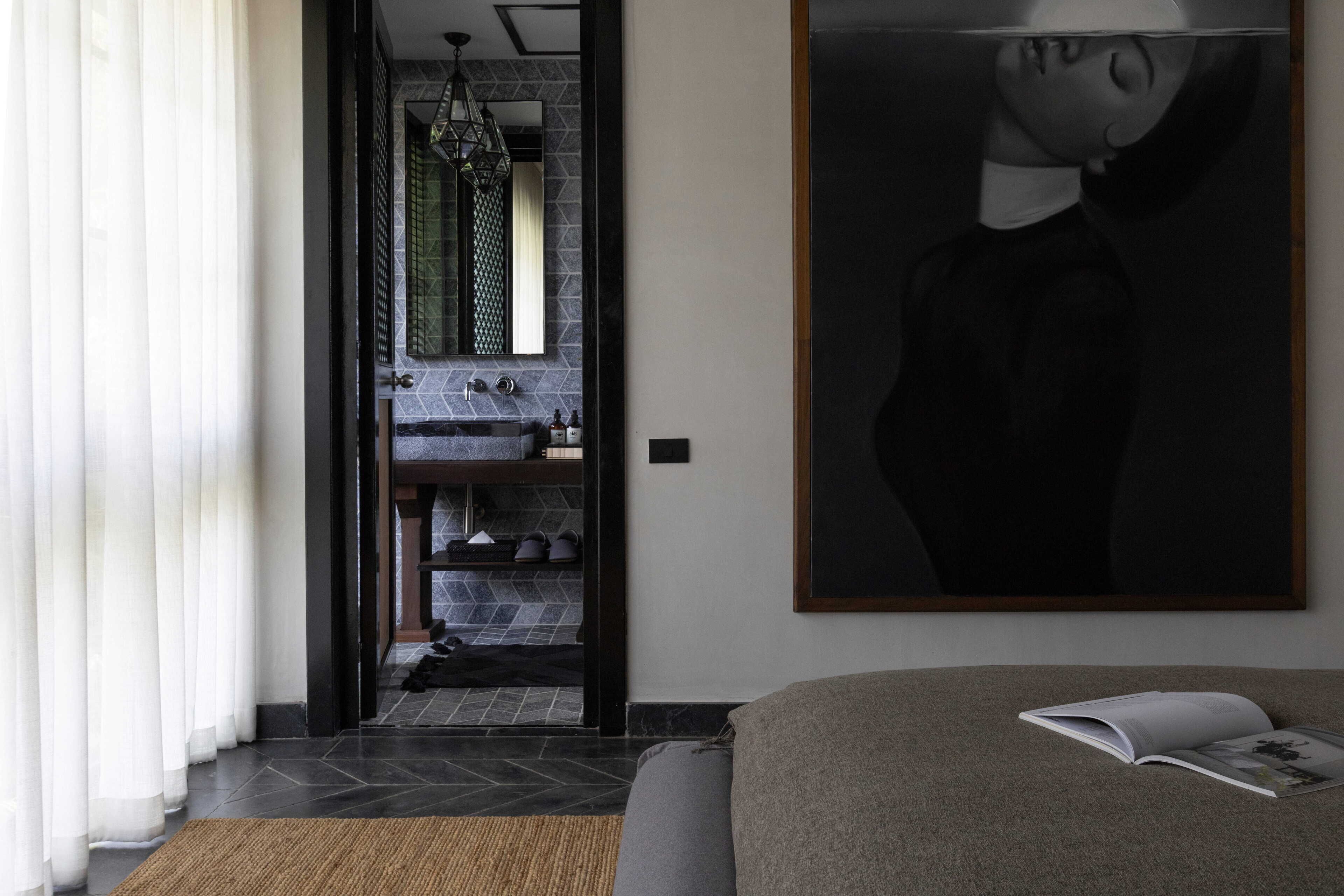 A modern room with a large bed, a reading area, and a view of a bathroom with a tiled backsplash.