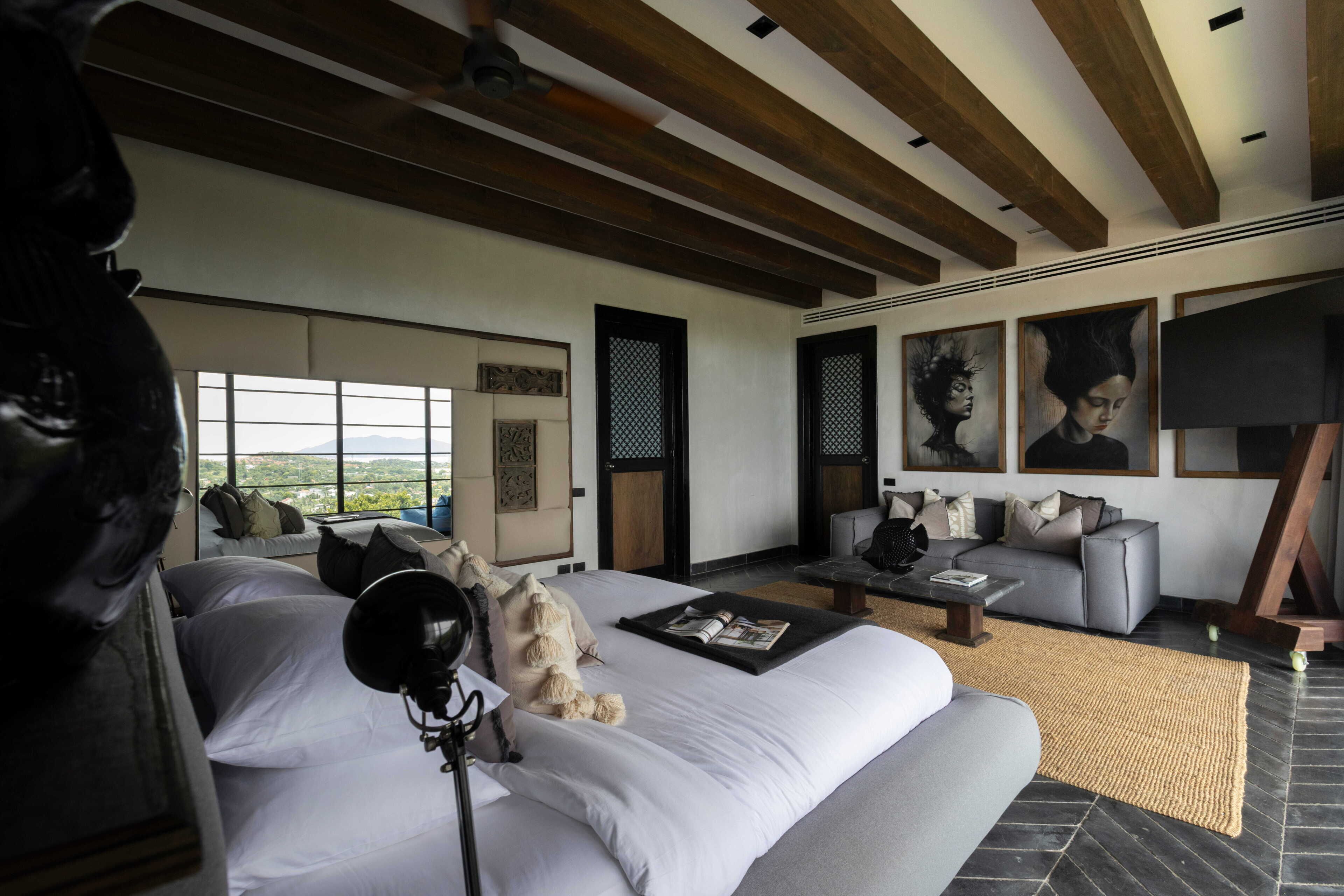 A modern hotel room with a large bed, a sofa, a coffee table, and artwork on the walls.