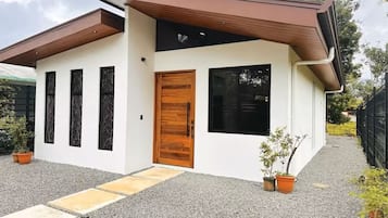 A modern house with a wooden door, large windows, and a gravel driveway.
