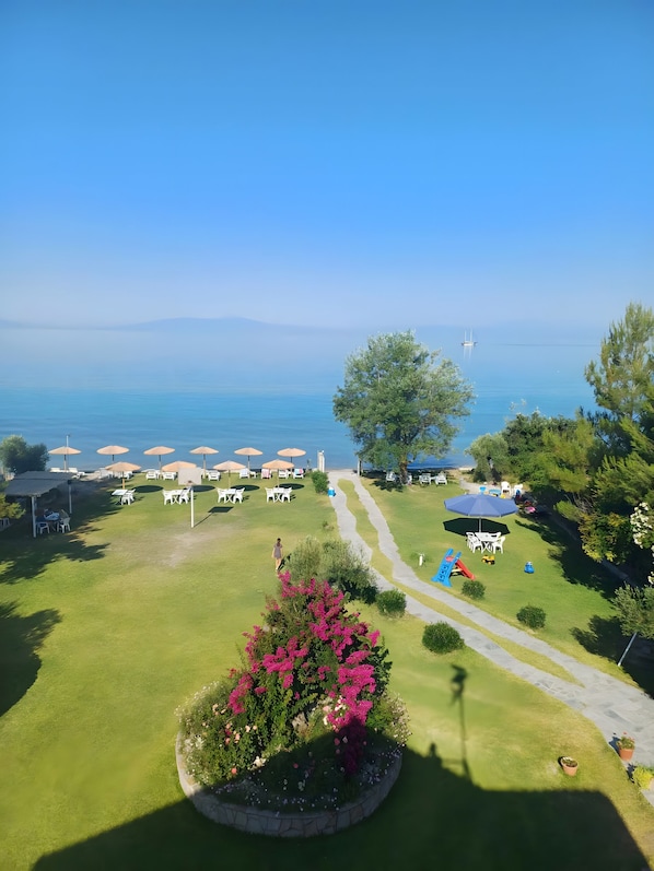 A coastal resort with a grassy lawn, outdoor seating, and a clear view of the sea. - Apartment 'Marina's Houses By The Sea - Apt 6' with Sea View, Wi-Fi and Air Conditioning (Kassandra)
