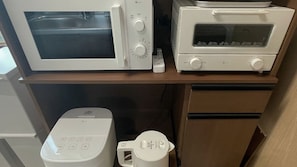 Una cocina con microondas, tostadora y cafetera sobre una encimera de madera.