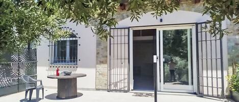 Un patio exterior con una parrilla, sillas y una puerta de cristal.