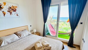 Habitación de hotel con una cama, un mapa mundial en la pared y vista al mar a través de la ventana.